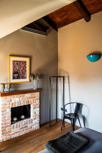 a living room with a brick fireplace and a chair at Boutique Hotel Al Palazzo Rosso in Neive