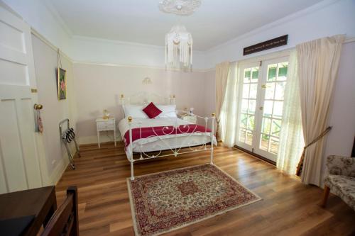 a bedroom with a white bed and a rug at Rosebridge House Bed & Breakfast Adult Retreat in Gooseberry Hill