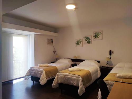 um quarto com quatro camas e uma janela em EMILIA HOTEL em Rosário