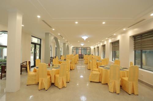 a banquet hall with tables and yellow chairs at MOMALI Hotel Ninh Binh in Ninh Binh