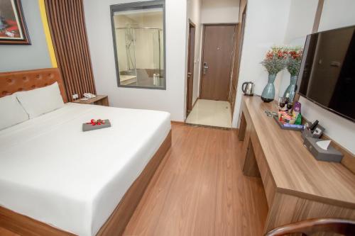 a bedroom with a large white bed and a television at MOMALI Hotel Ninh Binh in Ninh Binh