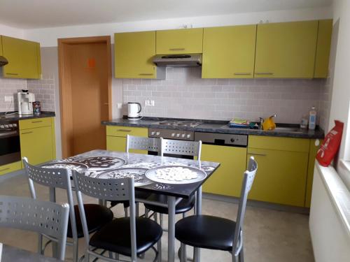 eine Küche mit gelben Schränken sowie einem Tisch und Stühlen in der Unterkunft Pension BERLIN in Spremberg in Spremberg