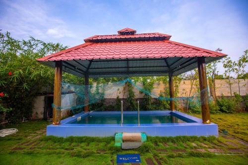 a gazebo with a pool in a yard at Waves Beach House in Puducherry