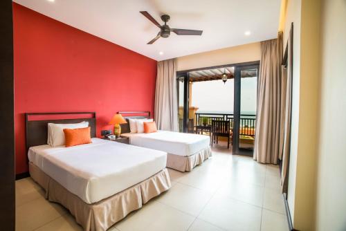 two beds in a room with a red wall at Pandanus Resort in Mui Ne