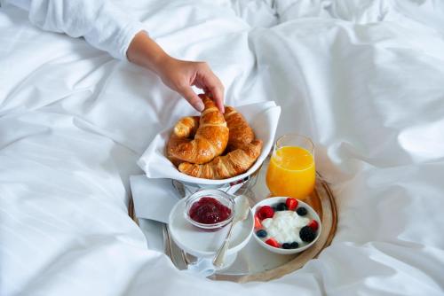 a person reaching for a tray of pastries and orange juice at Hotel Nassauer Hof in Wiesbaden