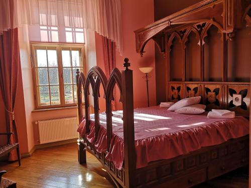 a bedroom with a large wooden bed with red sheets at Dundagas Pils in Dundaga