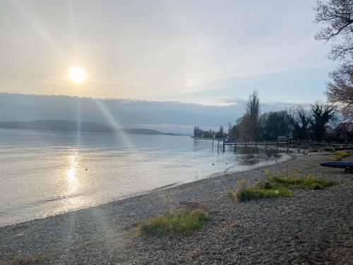 a beach with the sun shining on the water at Haus Münsterblick in Reichenau