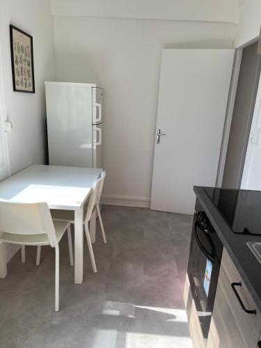 une salle à manger blanche avec une table et des chaises blanches dans l'établissement François Mitterand, à Elbeuf