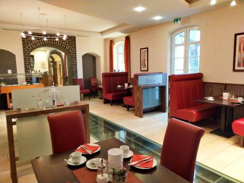 a restaurant with red chairs and a table and a dining room at Hotel Xtra Gleis in Hörstel