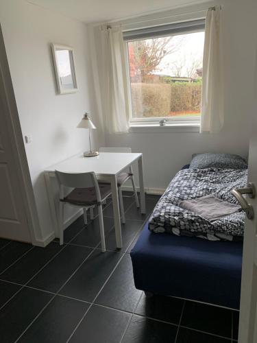 a bedroom with a bed and a table and a window at Your place in Herlev