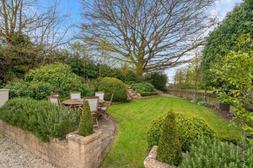 a garden with a table and chairs in a yard at Thatch Cottage in Todenham