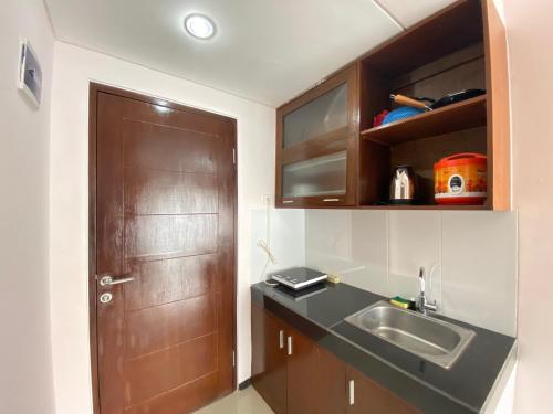 - une cuisine avec un évier et une porte en bois dans l'établissement Simply Homey 2BR Apartment at Gateway Pasteur By Travelio, à Bandung