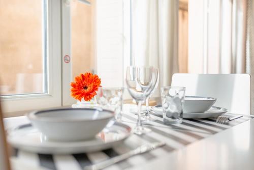 une table avec des assiettes et des verres et une fleur orange sur elle dans l'établissement Le 9ème- Métro Valmy-HomaLyon, à Lyon
