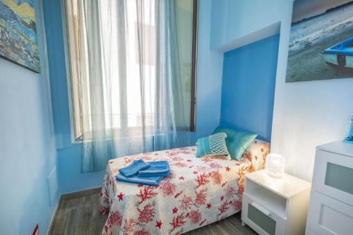 a blue bedroom with a bed and a window at Liberty House (by Vacation Service) in Cefalù
