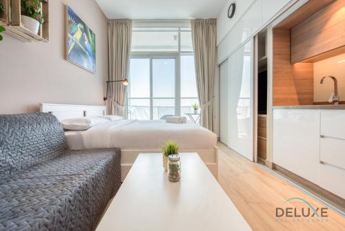 a hotel room with a bed and a couch and a table at Playful Studio in Studio One Dubai Marina by Deluxe Holiday Homes in Dubai