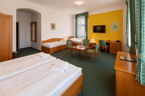 a hotel room with two beds and a desk at Hotel U Sládka in Chodová Planá