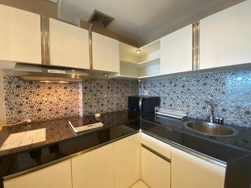 a kitchen with white cabinets and a sink at Deluxe & Well Appointed 2BR at El Royale Apartment By Travelio in Bandung