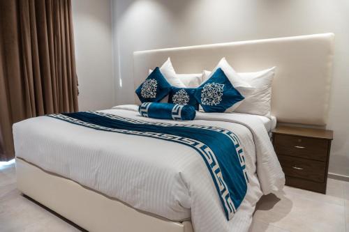 a bedroom with a bed with blue and white pillows at Trivelles Executive Suites Islamabad in Islamabad