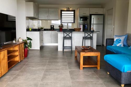 a living room with a blue couch and a kitchen at Alicia's Sky flat on the heights with nice view on the sea and Papeete in Papeete