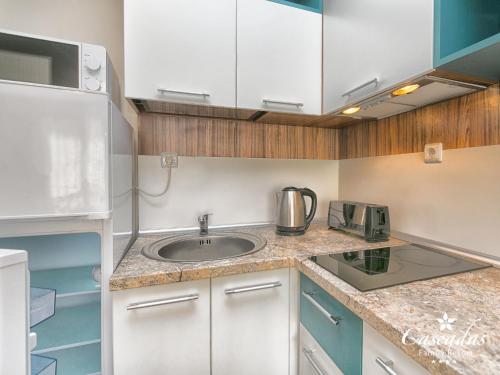 a small kitchen with a sink and a refrigerator at Cascadas Family Resort in Sunny Beach