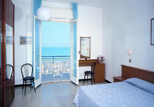 a bedroom with a bed and a desk and a balcony at Grand Hotel Excelsior in Senigallia