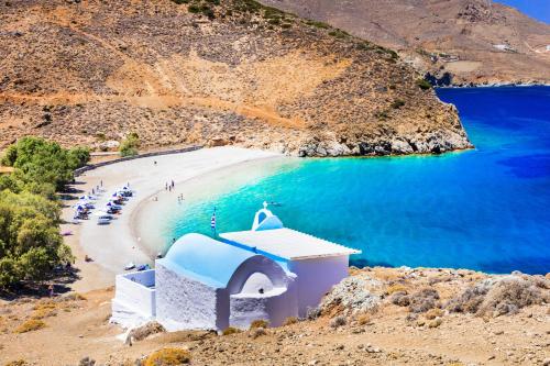 a chapel on a beach with blue water at Astropalia Luxury Studios in Astypalaia Town