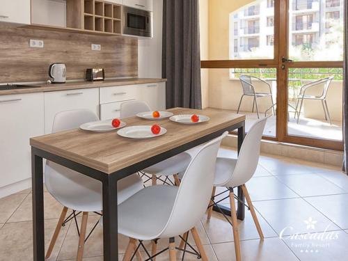 a kitchen with a wooden table and white chairs at Cascadas Family Resort in Sunny Beach
