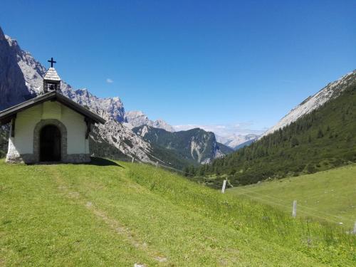 a small chapel on a hill with mountains in the background at Haus Witting in Leutasch