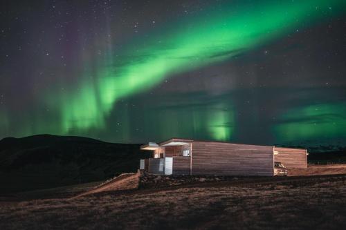 a building under the northern lights in a field at Black Beach Suites in Vík