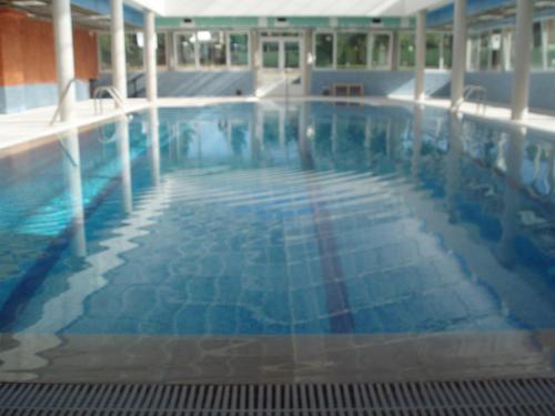a large swimming pool with blue water in a building at Apartamentos Monte Hernanz in Riaza