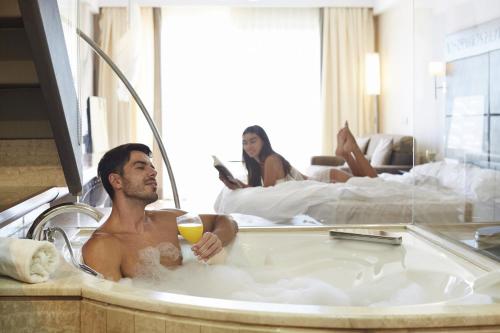 a man sitting in a bathtub in a hotel room at Insotel Fenicia Prestige Suites & Spa in Santa Eularia des Riu