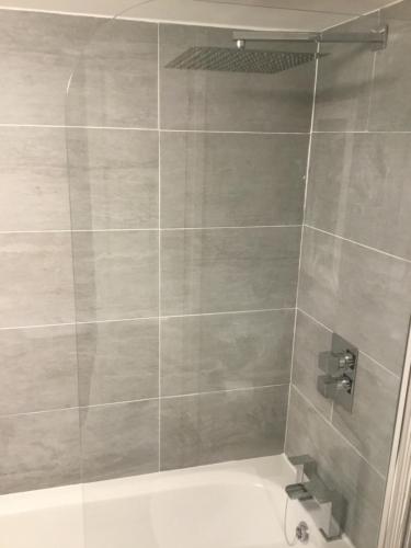 La salle de bains est pourvue d'une douche et d'une baignoire blanche. dans l'établissement Beach cottage, à Gorleston-on-Sea