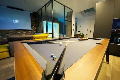 a pool table in a living room with ahibition at Capsule Gaming balnéo & billard & babyfoot & sauna 2 chambres in Valenciennes