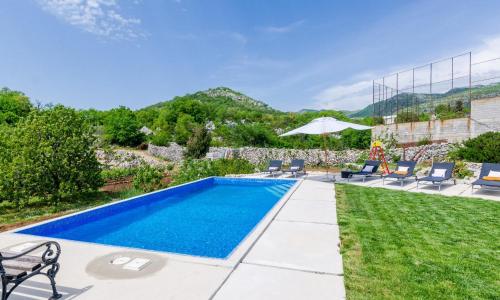 una piscina en un patio con sillas y sombrilla en Villa Majkovica, en Orasac