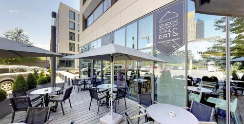 an outdoor patio with tables and chairs and umbrellas at Novotel Suites Luxembourg in Luxembourg