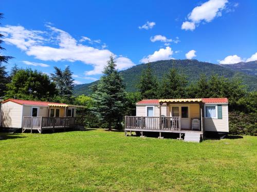 a group of cottages in a field with mountains in the background at Club del Sole Due Laghi Levico Family Collection in Levico Terme