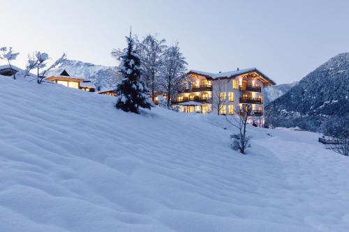a house on a snow covered hill in the snow at Hotel Ritzlerhof - Panorama und Spa in Sautens