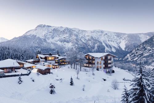 a resort in the snow with mountains in the background at Hotel Ritzlerhof - Panorama und Spa in Sautens