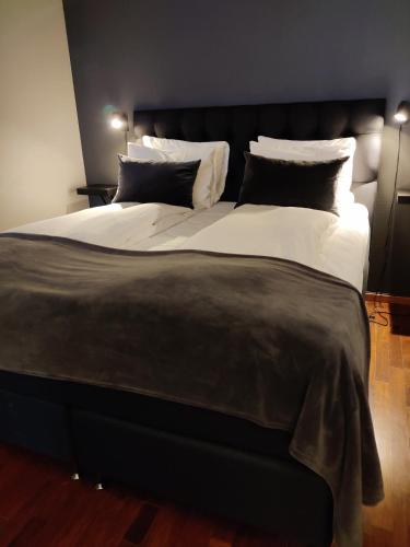 a large bed with black and white sheets and pillows at First Hotel Millennium in Oslo