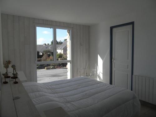 a white bedroom with a bed and a large window at REF 123 Maison T5 pour huit personnes proche plage à Arzon in Arzon