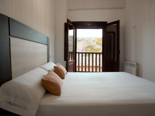 a bedroom with a large white bed with a window at Apartamento Subida Las Torres in Albarracín