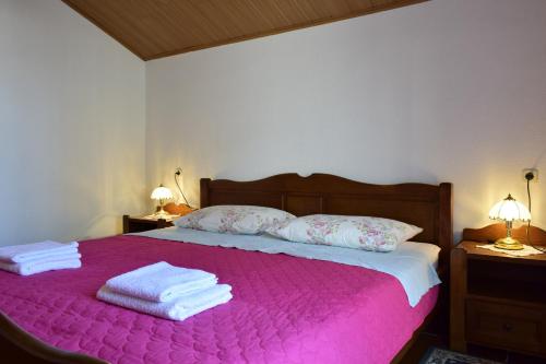 een slaapkamer met een roze bed en handdoeken bij Apartment Tommy in Malinska