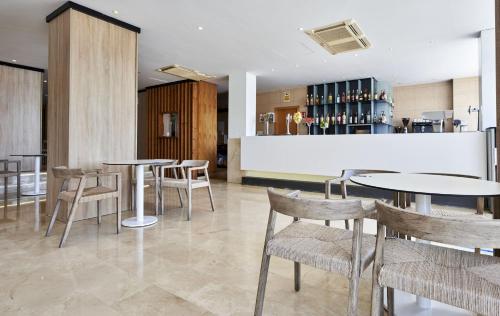 a restaurant with tables and chairs and a bar at Globales Cala Viñas Adults Only 16+ in Cala Vinyes