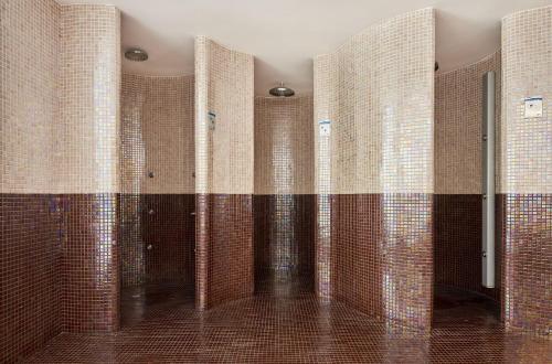 a bathroom with brown and white tiled walls at Globales Cala Viñas Adults Only 16+ in Cala Vinyes