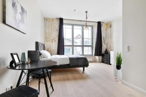 a bedroom with a bed and a table and a window at Hilltop Apartments - Noblessner District in Tallinn