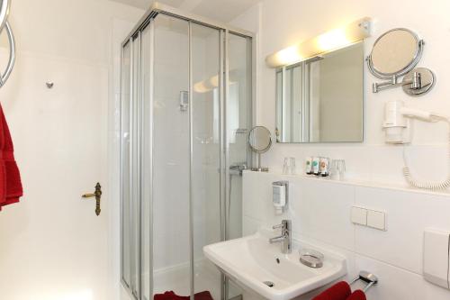 a white bathroom with a sink and a shower at Hotel Rathausglöckel in Baden-Baden