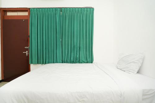 a bedroom with a bed with a green curtain at Merapi Inn Syariah by ecommerceloka in Surabaya