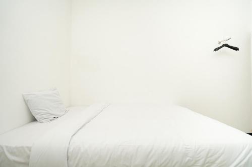 a white bed in a white room with aigil at Merapi Inn Syariah by ecommerceloka in Surabaya