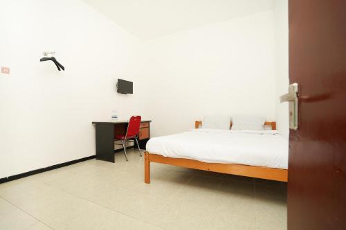 a bedroom with a bed and a desk with a television at Merapi Inn Syariah by ecommerceloka in Surabaya