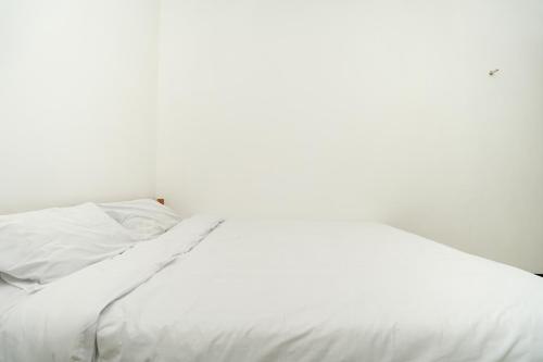 a white bed with white sheets and a pillow at Merapi Inn Syariah by ecommerceloka in Surabaya